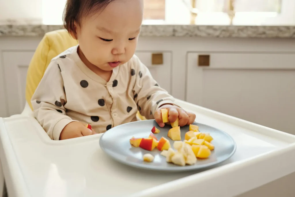 Baby eating fruit off plate
